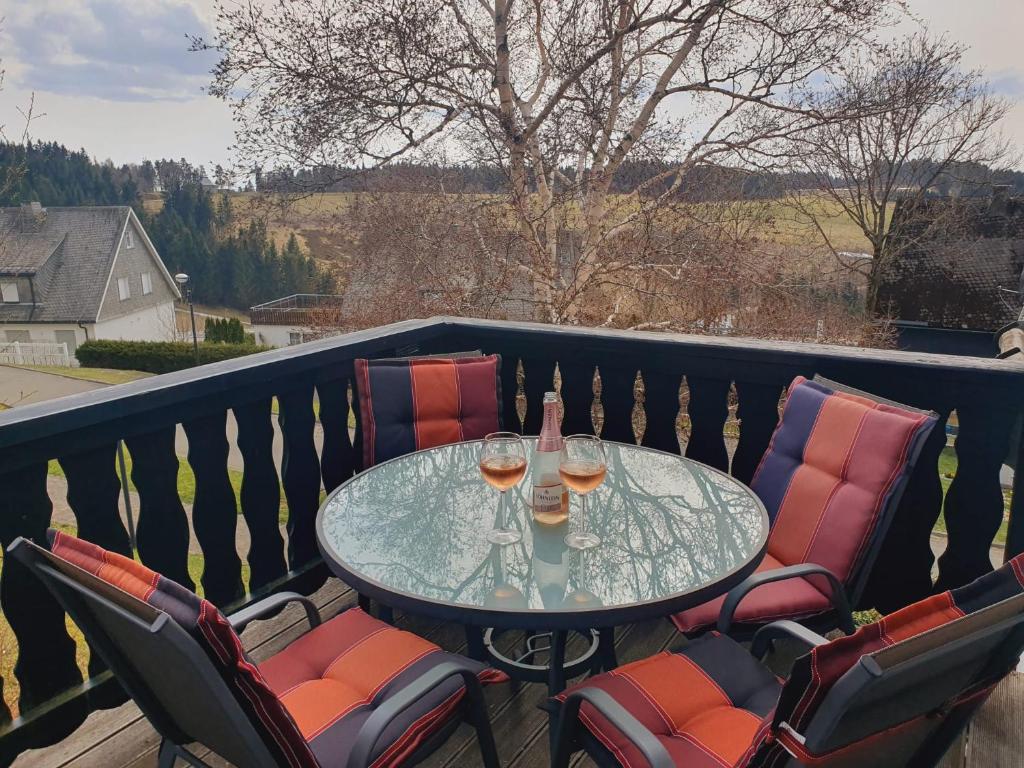 a glass table with wine glasses on a balcony at Altastenberger Lodge in Winterberg