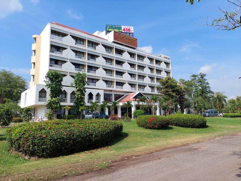 un gran edificio blanco con arbustos delante en Phuphanplace Hotel, en Ban Phang Khwang Tai