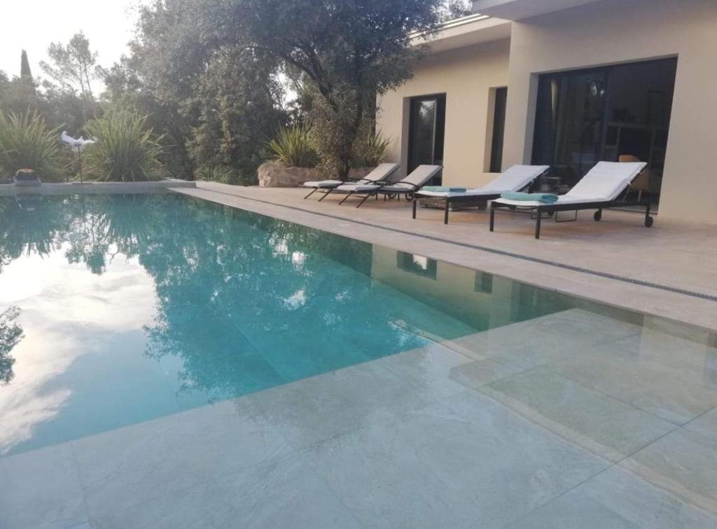 a swimming pool with lounge chairs next to a house at La Villa Kallisté in Vacquières