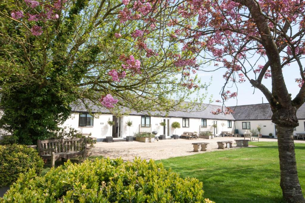 a view of the courtyard of a white building with pink flowers at Stable Cottage, Whitebridge Farm in Shaftesbury
