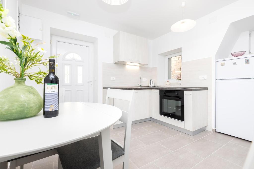 a white kitchen with a bottle of wine on a table at Apartment Morris in Veli Lošinj