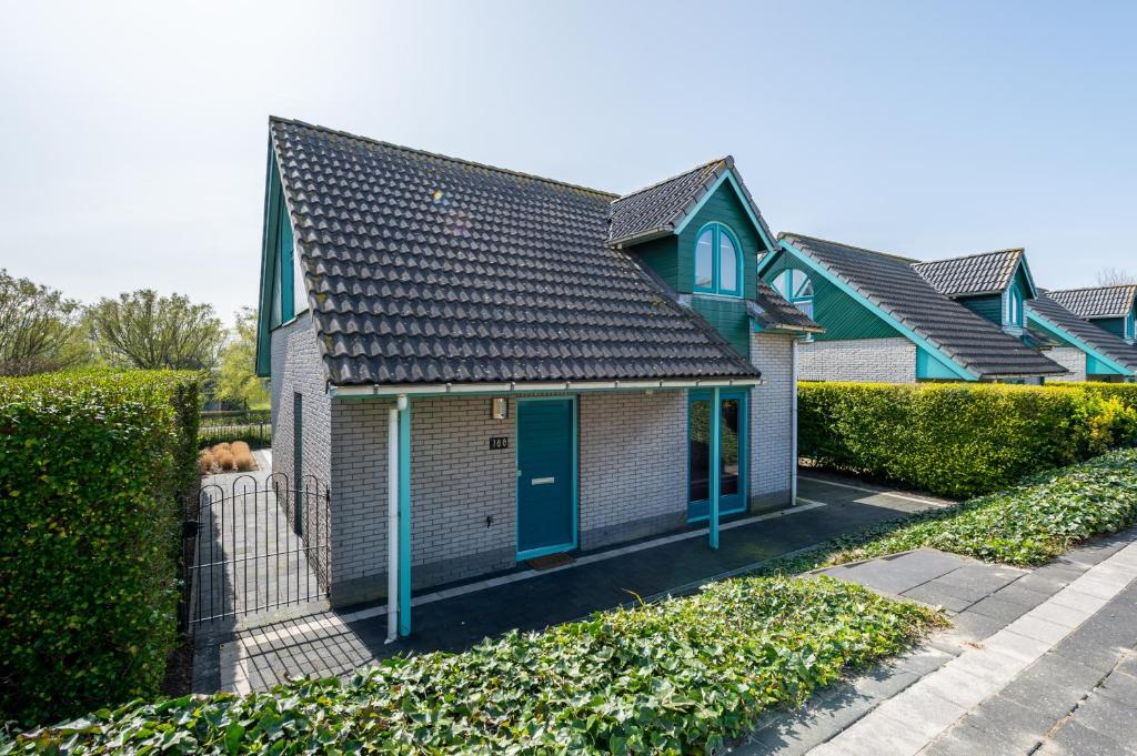 ein Haus mit blauen Türen und einem Zaun in der Unterkunft Bandol 186 - Kustpark Village Scaldia in Hoofdplaat