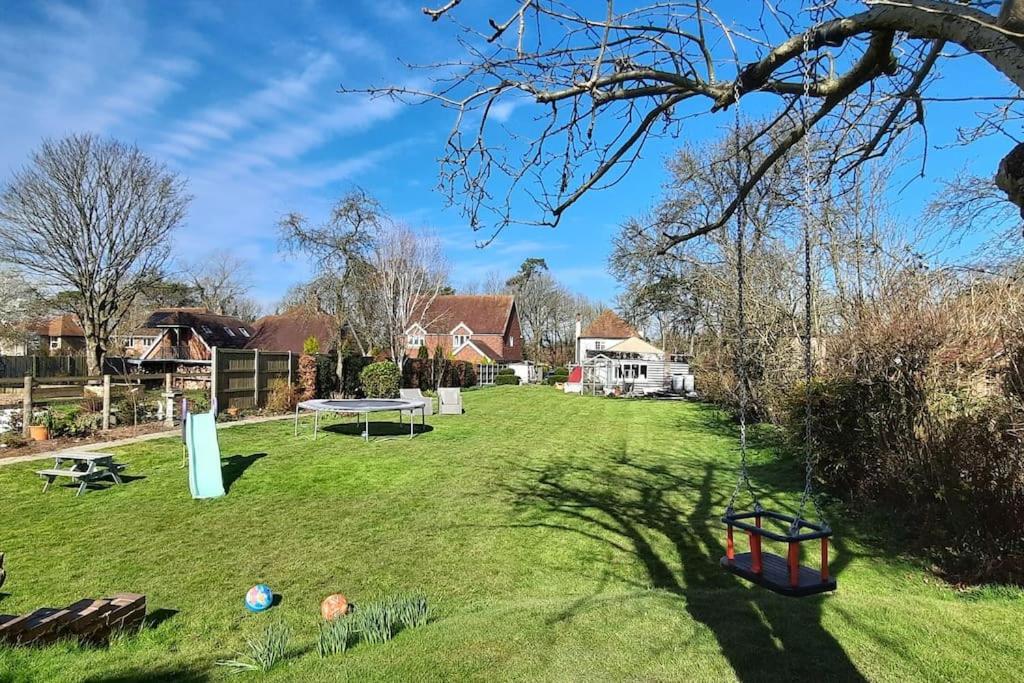 um grande quintal relvado com uma mesa e um parque infantil em Sycamore Lodge Kent With EV Zappi type 2 em Sellindge