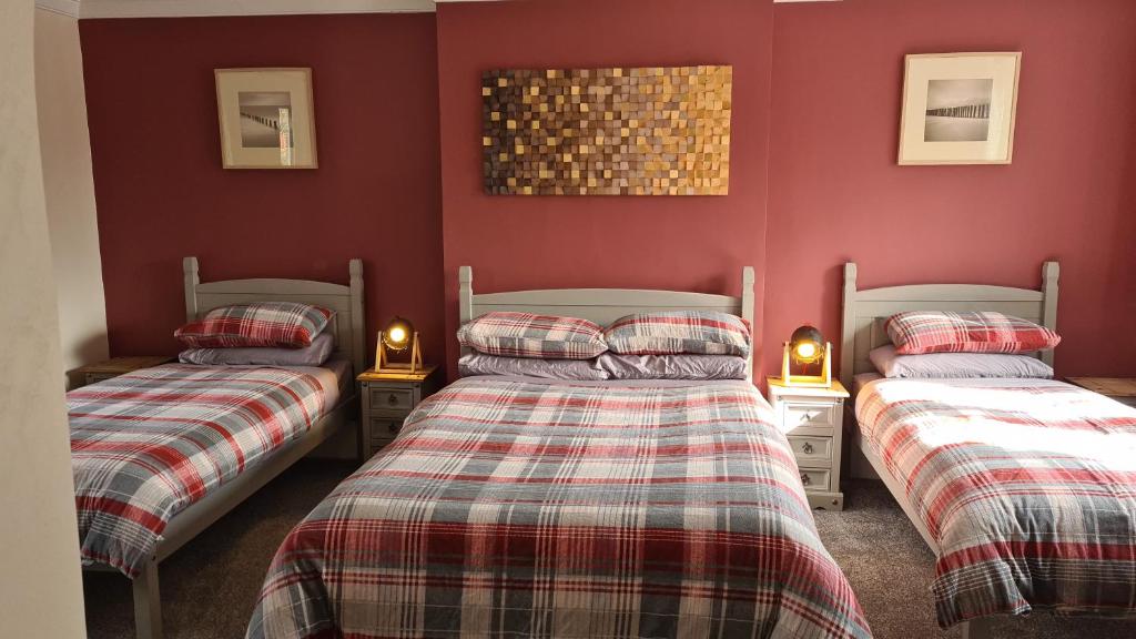 Tudor Lodge Hotel في نوتينغهام: سريرين توأم في غرفة بجدران حمراء