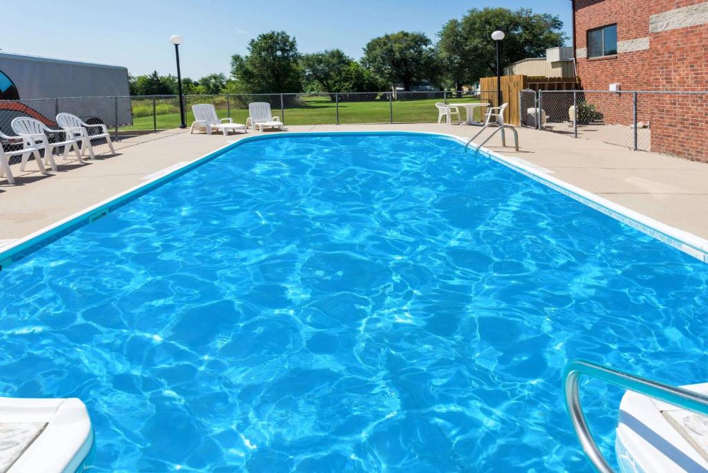 a large blue swimming pool with chairs in a patio at Super 8 by Wyndham Chanute in Chanute