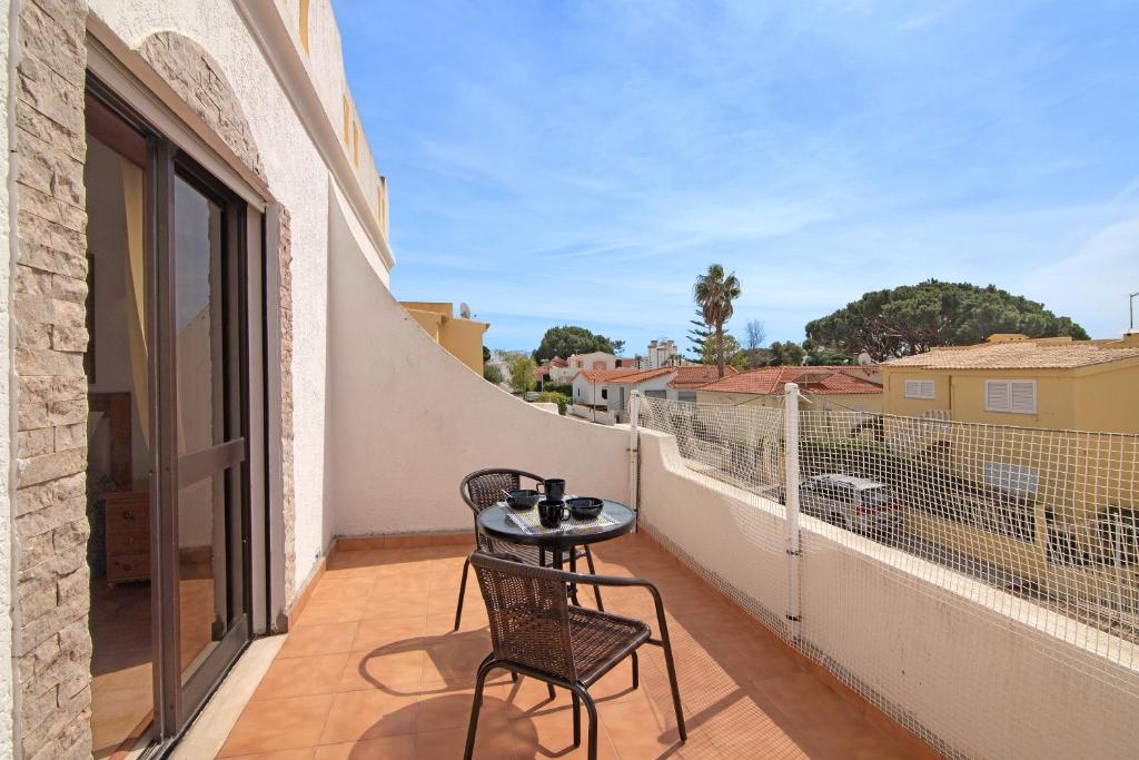 een patio met 2 stoelen en een tafel op een balkon bij Villa Fernando in Quarteira