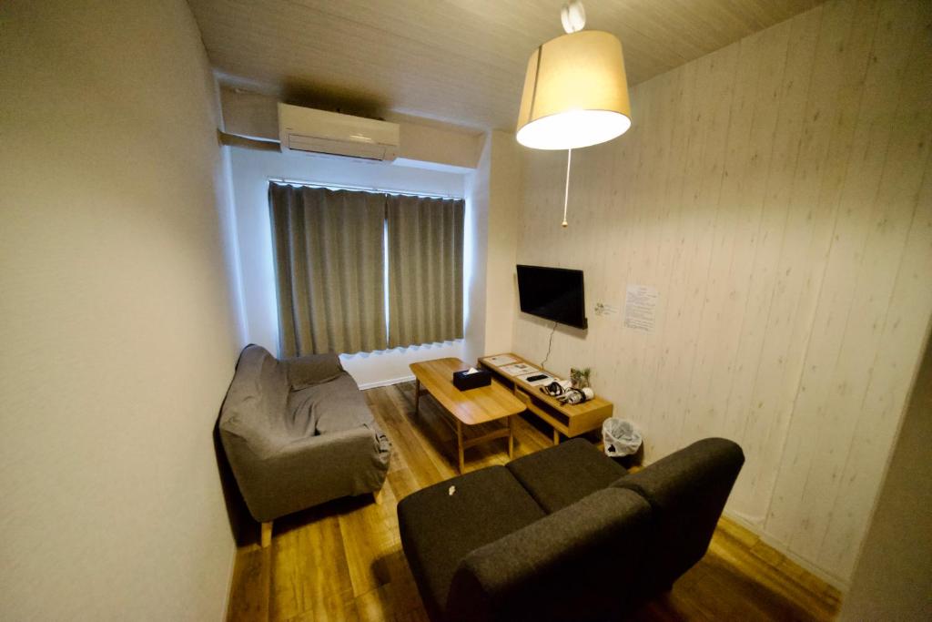 uma sala de estar com um sofá e uma mesa em Guest House Re-worth Yabacho1 402 em Nagoia