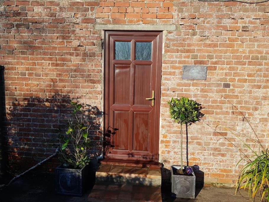 a red door on a brick building with potted plants at Amazingly quiet and peaceful studio getaway. in Woodhall Spa