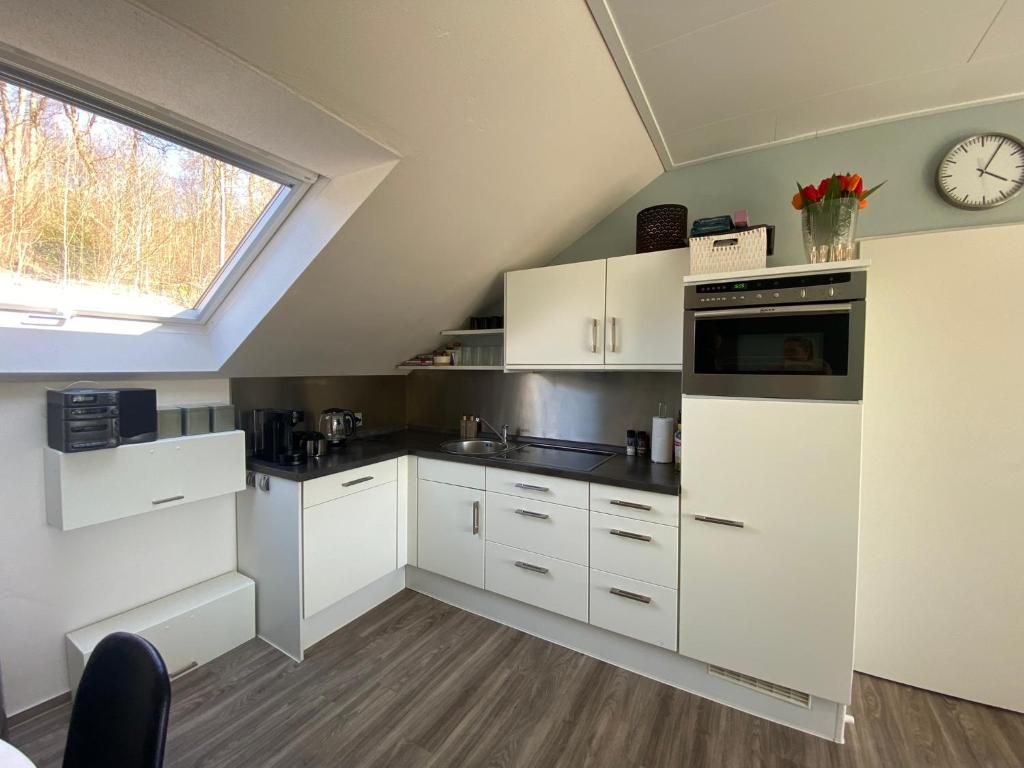 a kitchen with white cabinets and a clock on the wall at Ferienwohnung An der Spitze in Winterberg