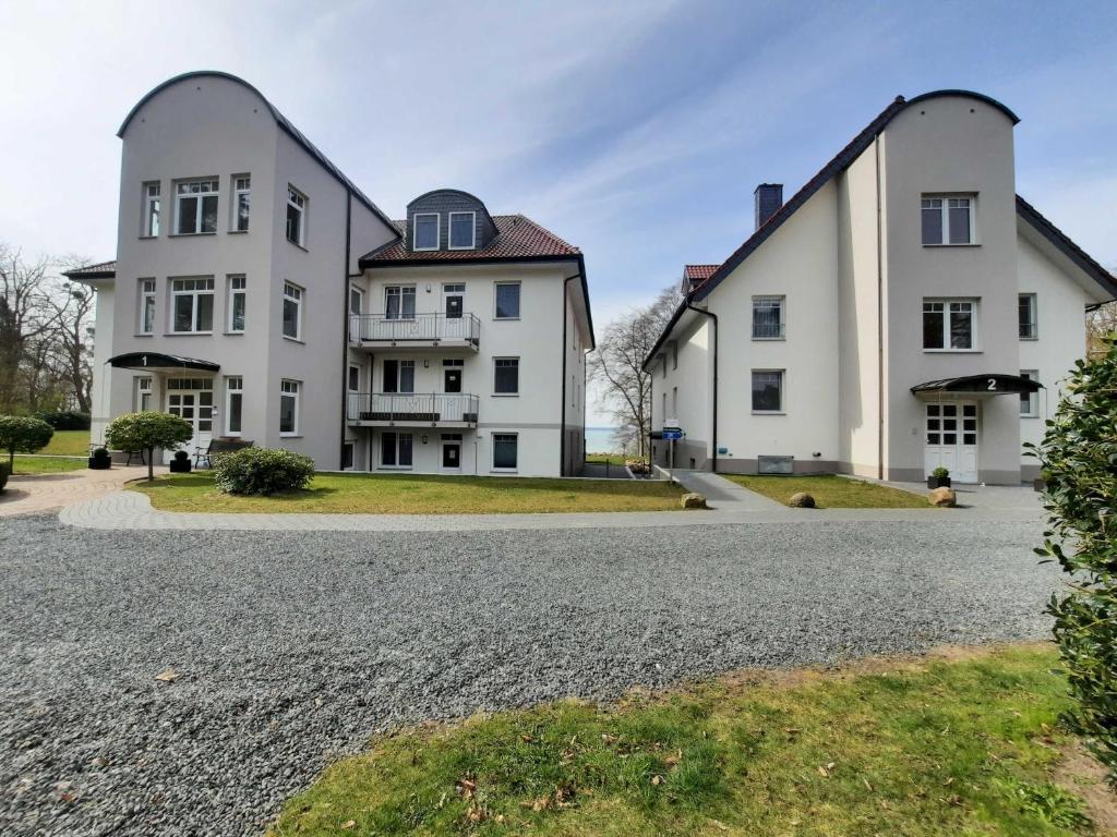 een huis met twee grote witte gebouwen op een grindoprit bij Haus am Kölpinsee FW Seejuwel Objekt ID 13833-4 in Kölpinsee