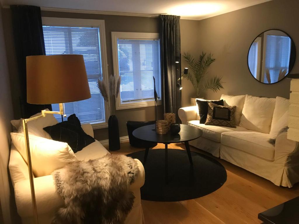 a living room with two white couches and a table at Victoriagården in Grimstad