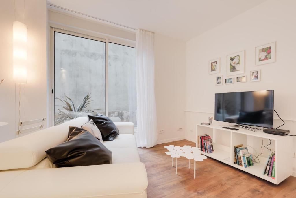 - un salon blanc avec un canapé blanc et une télévision dans l'établissement GuestReady - Amazing Ivory Flat - Tête d'Or Park, à Lyon
