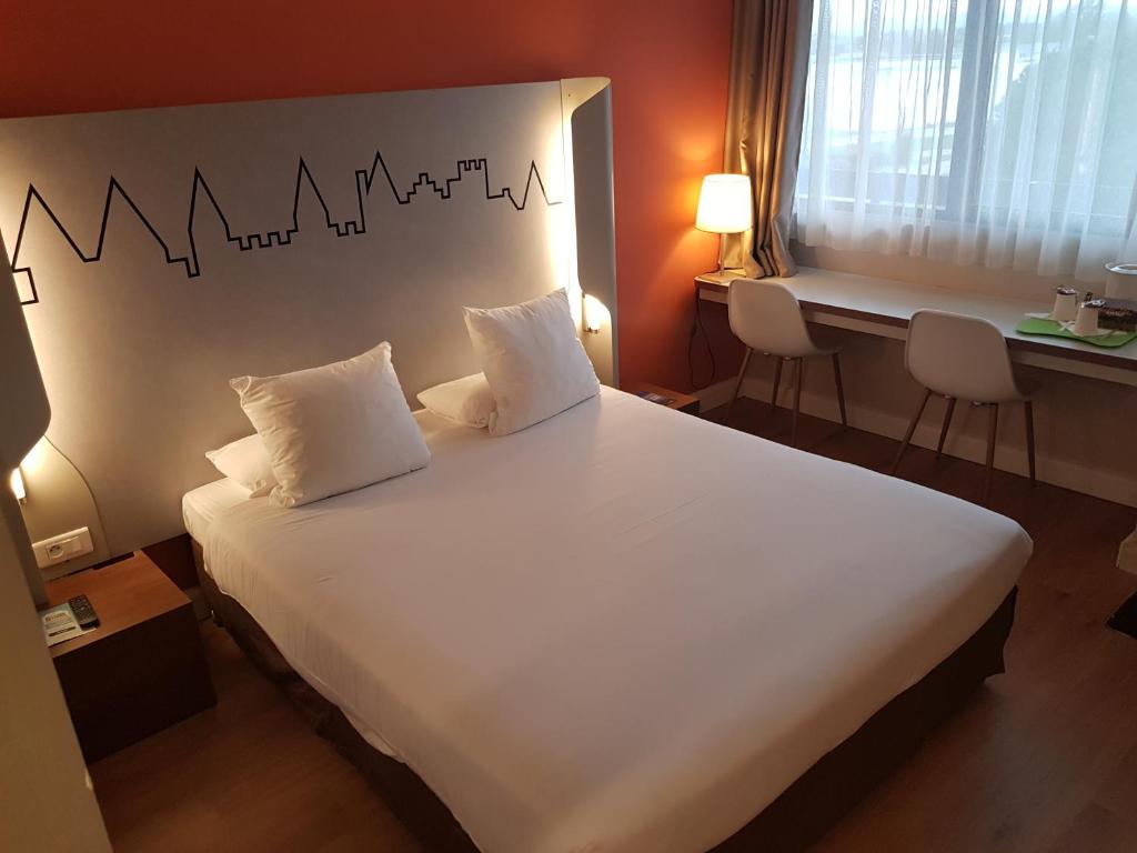- une chambre avec un grand lit blanc et 2 oreillers dans l'établissement Kyriad Carcassonne - Aéroport, à Carcassonne