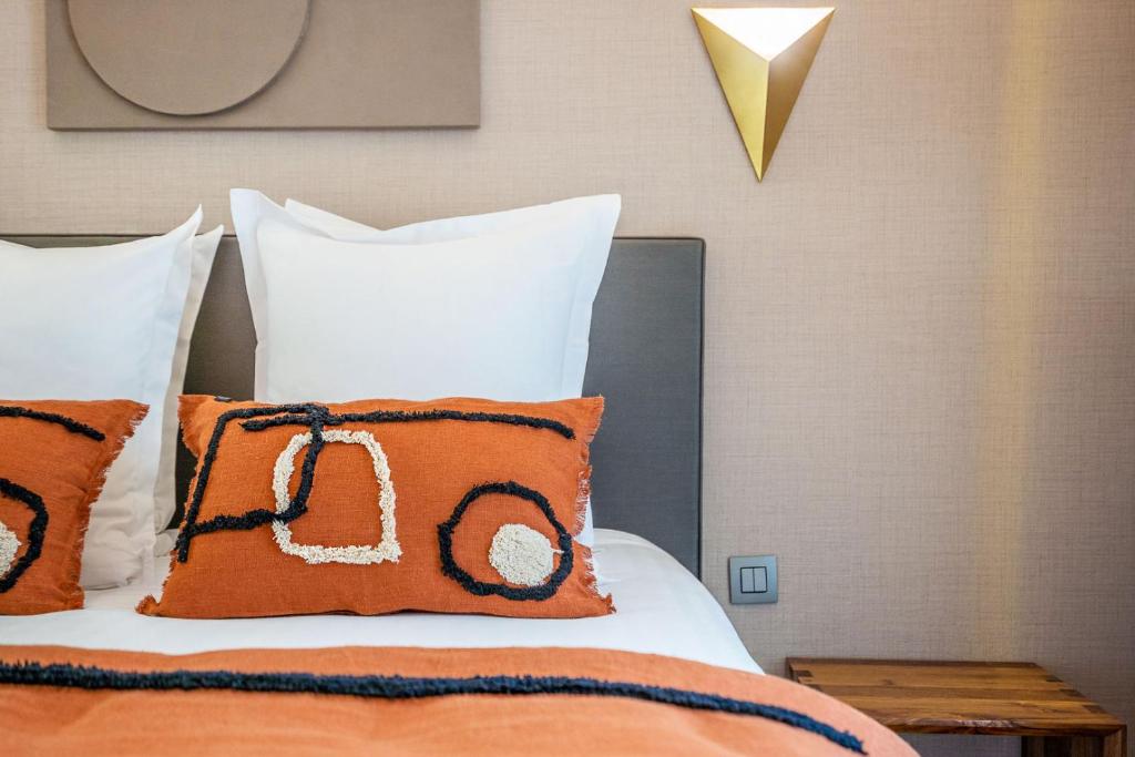 a bed with orange and white pillows on it at Yuna Les Halles - Serviced Apartments in Paris