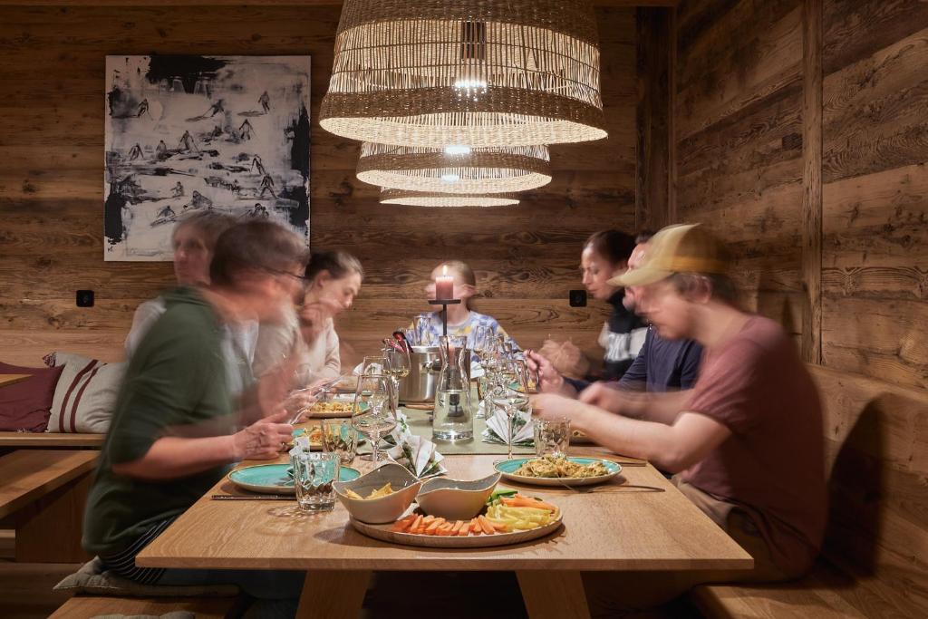 a group of people sitting around a table with food at Berghaus Schröcken - Hotel Apartments Spa in Schröcken