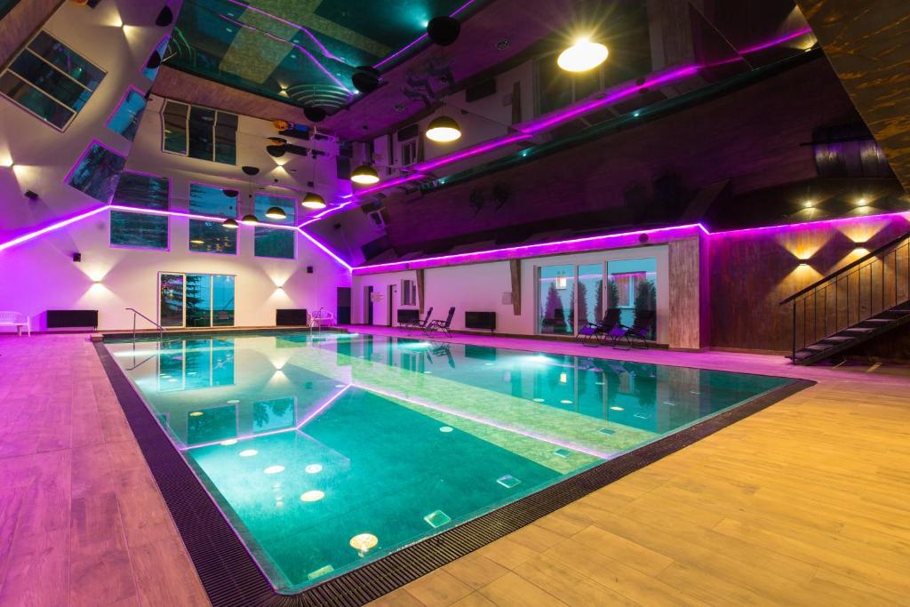una gran piscina en un edificio con luces moradas en Paradiso Park en Pobierowo