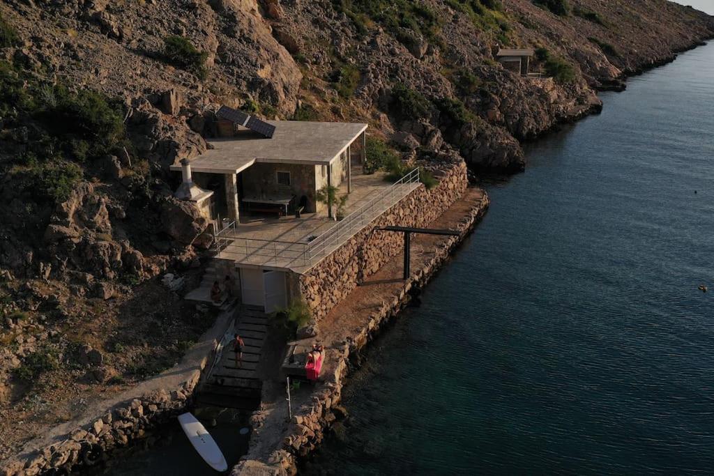 a house on the side of a mountain next to the water at Apartman Bačarije,Pag-Prizna in Seline