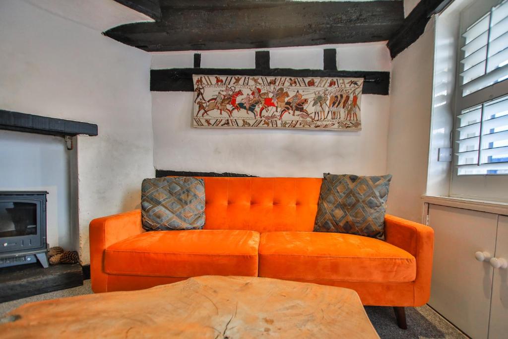 um sofá laranja numa sala de estar com lareira em Fisherman's Cottage! em Hastings