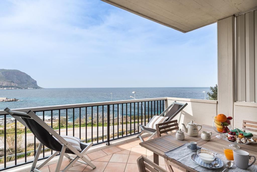 ein Balkon mit Tisch und Stühlen und dem Meer in der Unterkunft Mondello in Terrazza by DomuSicily in Mondello