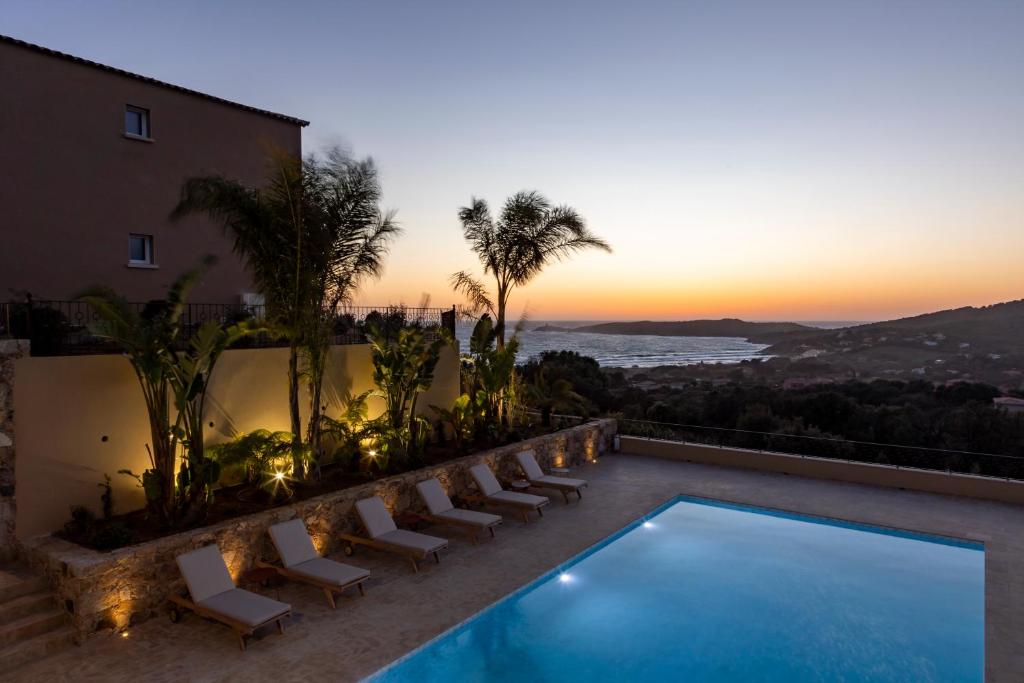 een villa met een zwembad en een zonsondergang bij Résidence Omigna in Cargèse