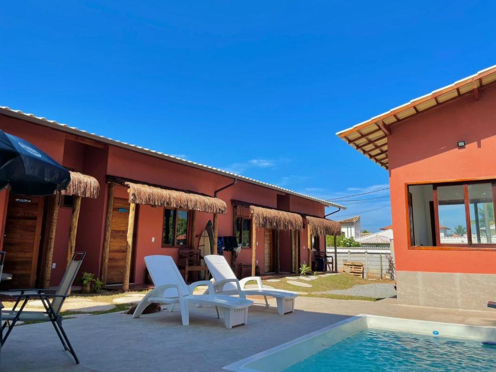 a house with two chairs and a swimming pool at Pousada Reserva de Itaúna in Saquarema