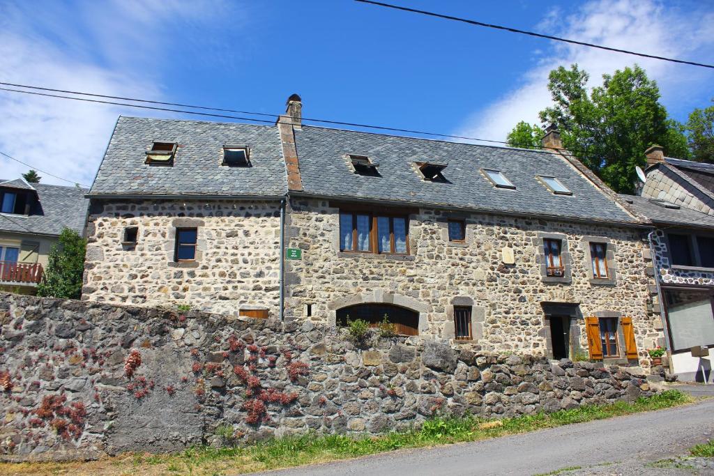 ein altes Steinhaus mit einer Steinmauer in der Unterkunft Maison de Varennes in Chambon-sur-Lac