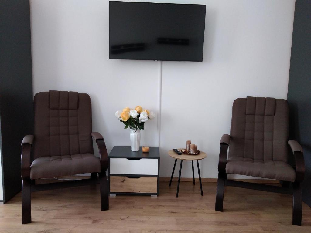 2 Stühle und ein Tisch mit einem TV an der Wand in der Unterkunft Apartmán Nad řekou in Vejprty