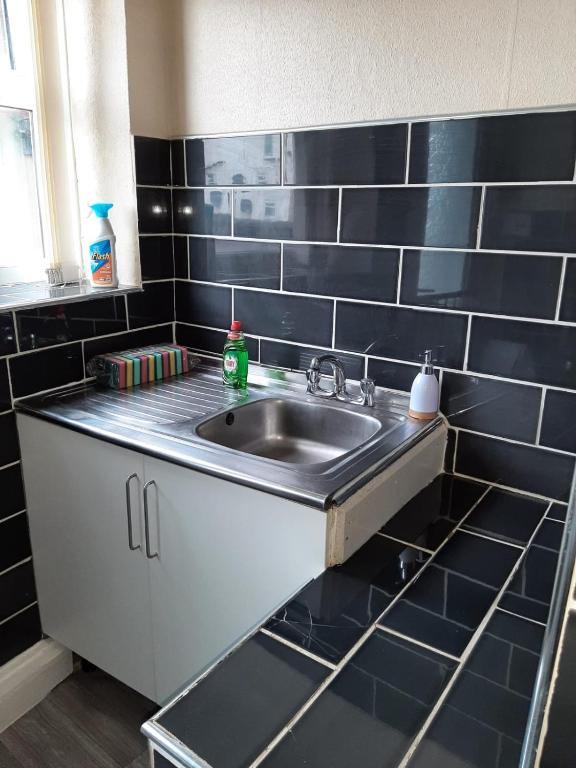 a kitchen with a sink and black tiled walls at Rhyl Aparthotels in Rhyl