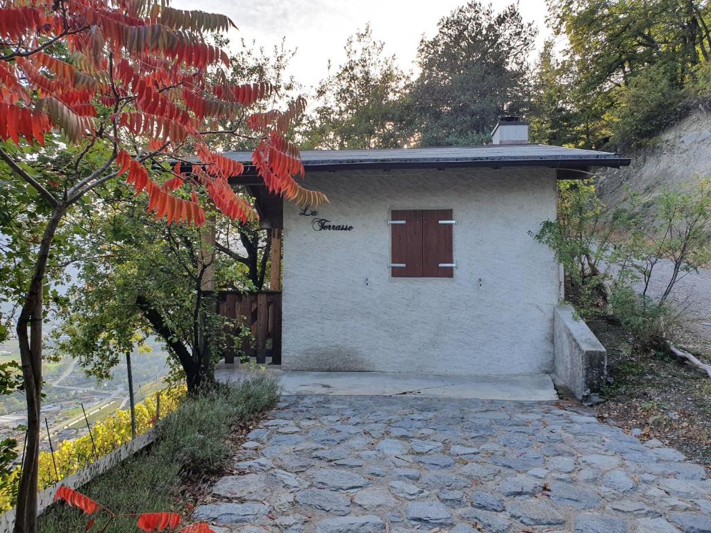 a small white building with a door and a tree at La Terrasse in Fully