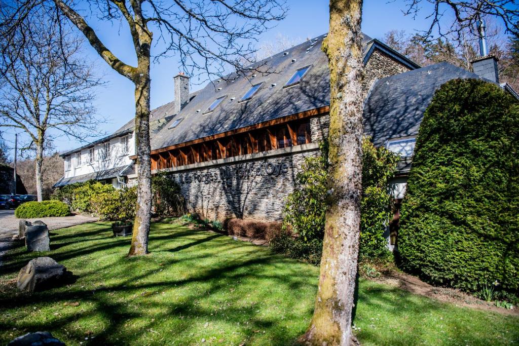 ein Haus mit einem Dach auf einem grünen Hof in der Unterkunft Hôtel Les Ardillières du Pont d'Oye in Habay-la-Neuve