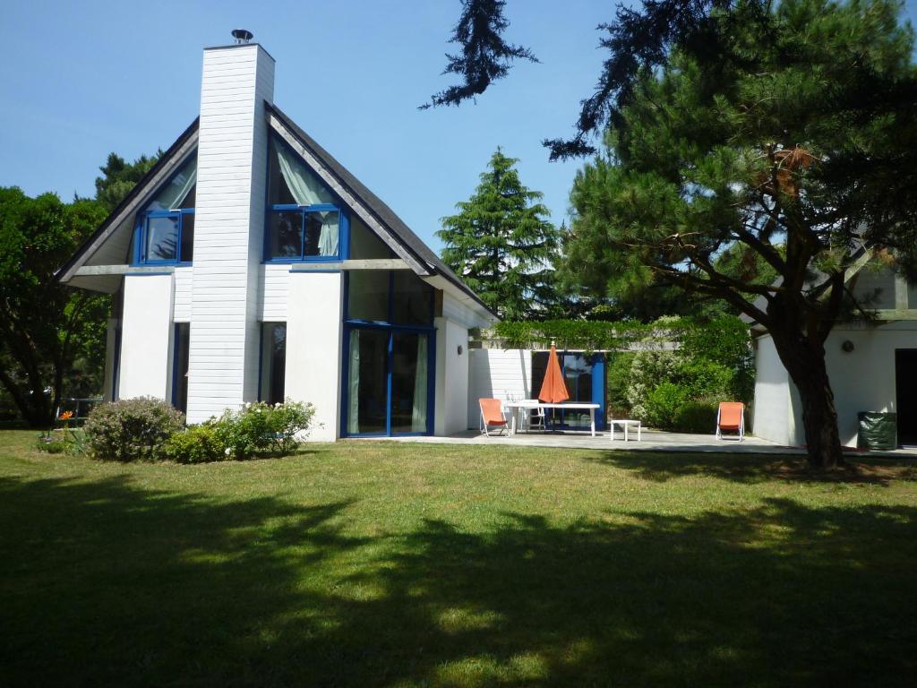 une maison avec deux chaises et une table dans une cour dans l'établissement Villa Spacieuse avec Beau Jardin, Wifi, Port a 500m, Trinite sur Mer, à La Trinité-sur-Mer