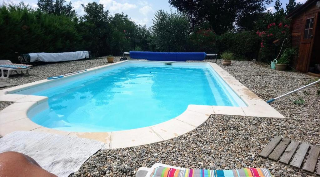 una piscina de agua azul en un patio en Chambre studio cuisine indépendant 2 pers piscine en Rousson
