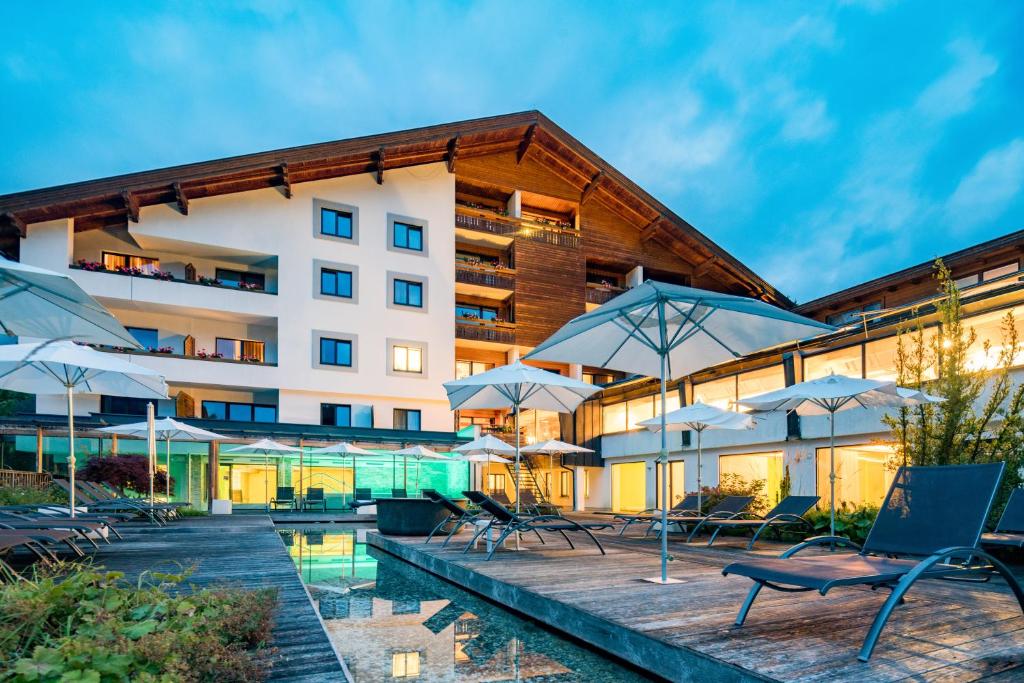 ein Hotel mit Stühlen und Sonnenschirmen neben einem Pool in der Unterkunft Hotel NockResort in Bad Kleinkirchheim