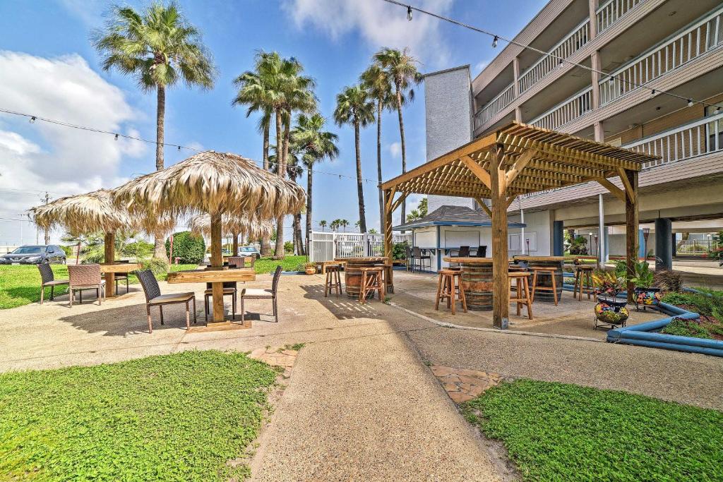 eine Terrasse mit Tischen, Sonnenschirmen und Palmen in der Unterkunft Beach Condo Balcony, Pool Access, Steps to Shore! in Corpus Christi