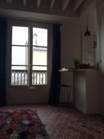 sala de estar con ventana grande y alfombra en Appartement Paris Marais, en París