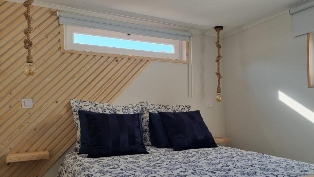 sypialnia z łóżkiem z niebieskimi poduszkami i oknem w obiekcie Family Surf Home - Casa do Páteo 5 - Aulas de Surf e Serviço de Compras w mieście Santo Isidoro