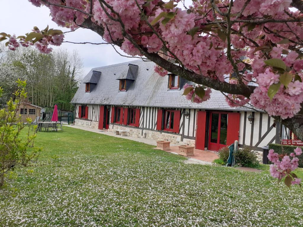 una casa con porte rosse e un albero con fiori rosa di Gîte des Bois Rimbert a Beuzeville