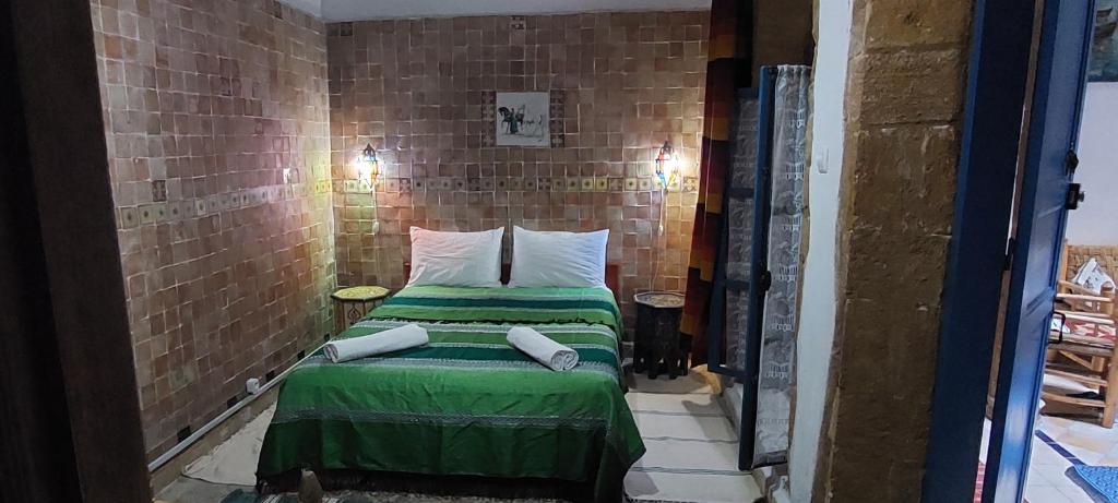 Cette petite chambre dispose d'un lit dans un mur en briques. dans l'établissement Riad Le Cheval Blanc, à Safi