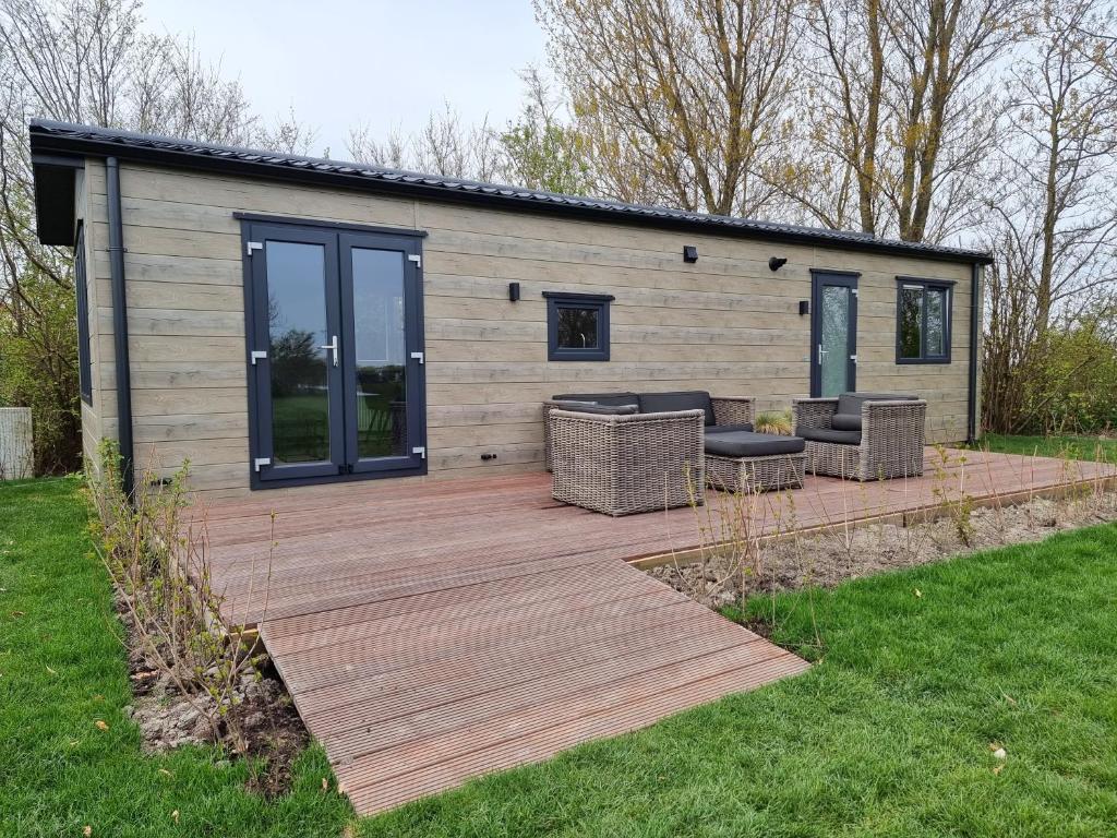 een huis met een houten terras in een tuin bij Luxe chalet AK09 Aagtekerke in Aagtekerke