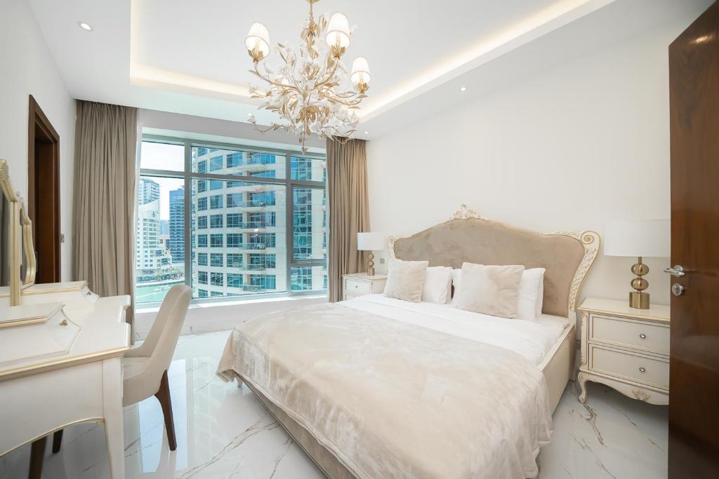 a white bedroom with a bed and a desk and a window at Luton Vacation Homes - Park Island, marina view-Dubai Marina-60AB5 in Dubai
