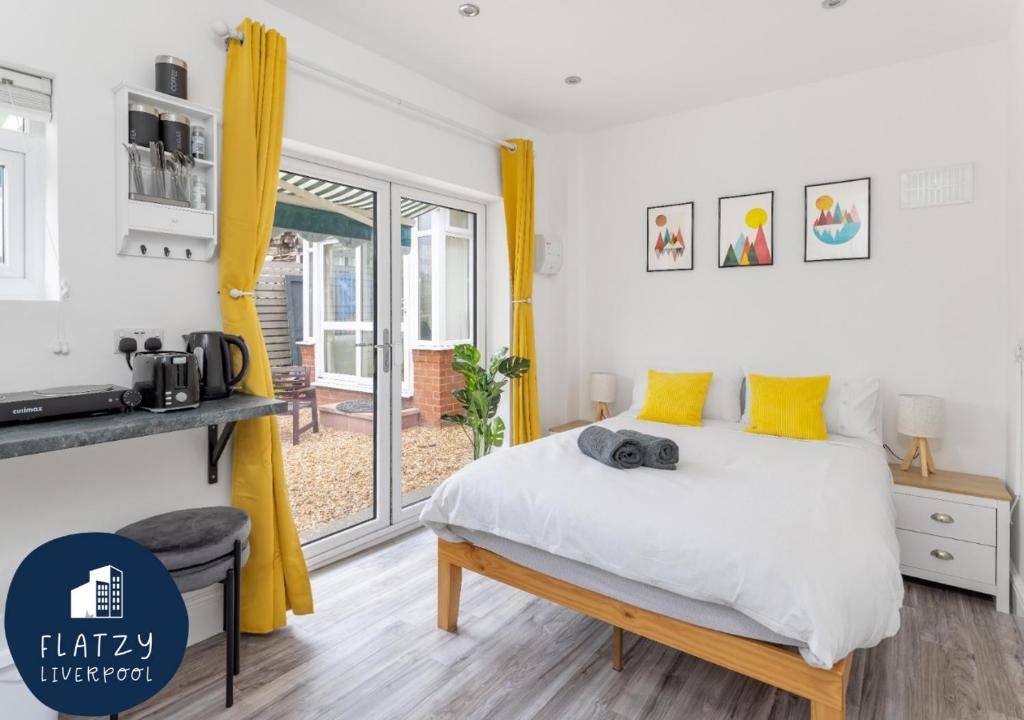 um quarto com uma cama grande e cortinas amarelas em Flatzy - Charming Garden Annexe in Aigburth with Kitchenette em Liverpool