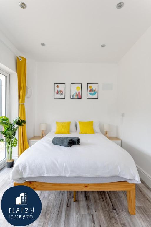 Hotel Flatzy - Charming Garden Annexe in Aigburth with Kitchenette, a bedroom with a bed with white sheets and yellow pillows at Flatzy - Charming Garden Annexe in Aigburth with Kitchenette in Liverpool