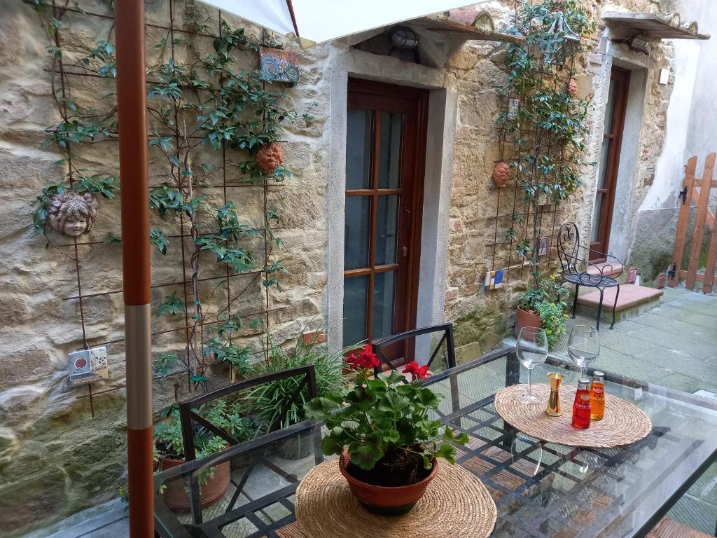 un patio al aire libre con 2 mesas y una sombrilla en LA BOTTEGA DEL CALZOLAIO, en Castiglion Fibocchi