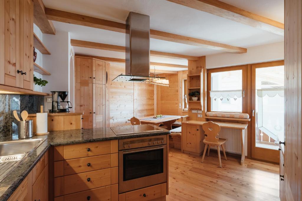 una cucina con armadi in legno e piano cottura. di BelaVal Apartments a La Villa