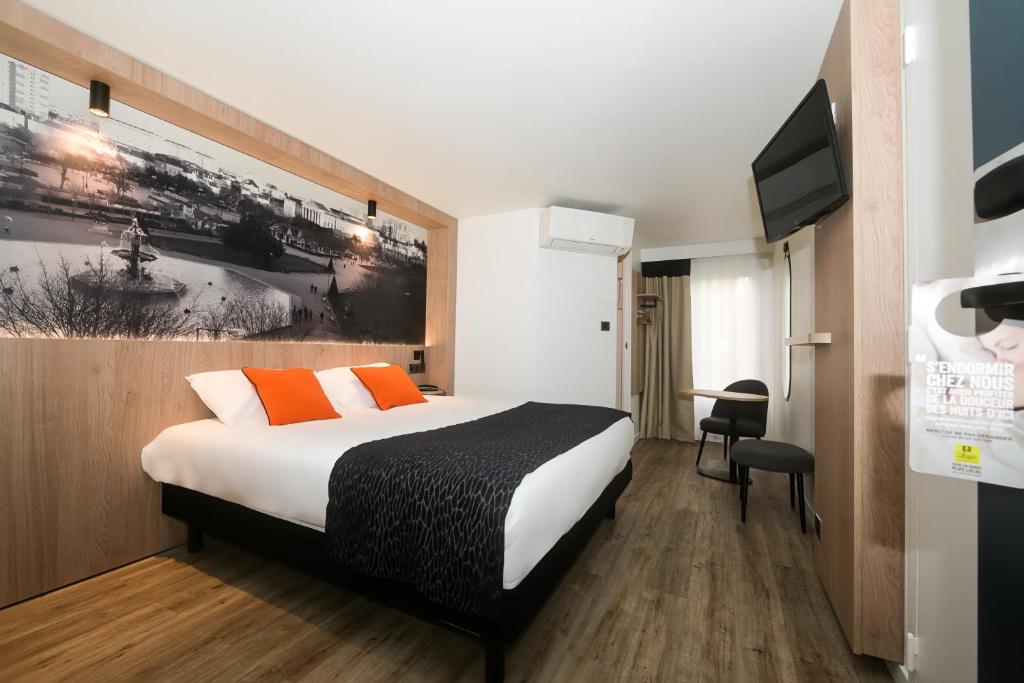 a hotel room with a bed and a tv at Logis Hôtel Angers Sud in Angers