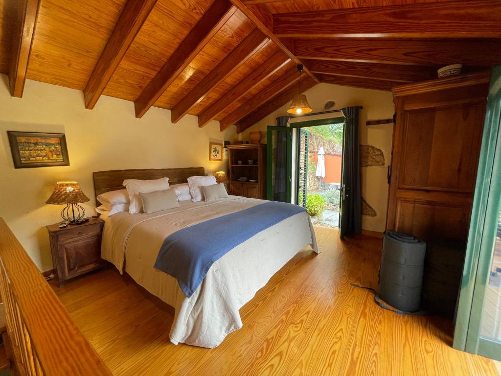 Un dormitorio con una cama grande en una habitación con techos de madera. en Dúplex de invitados en medio del bosque, en Firgas