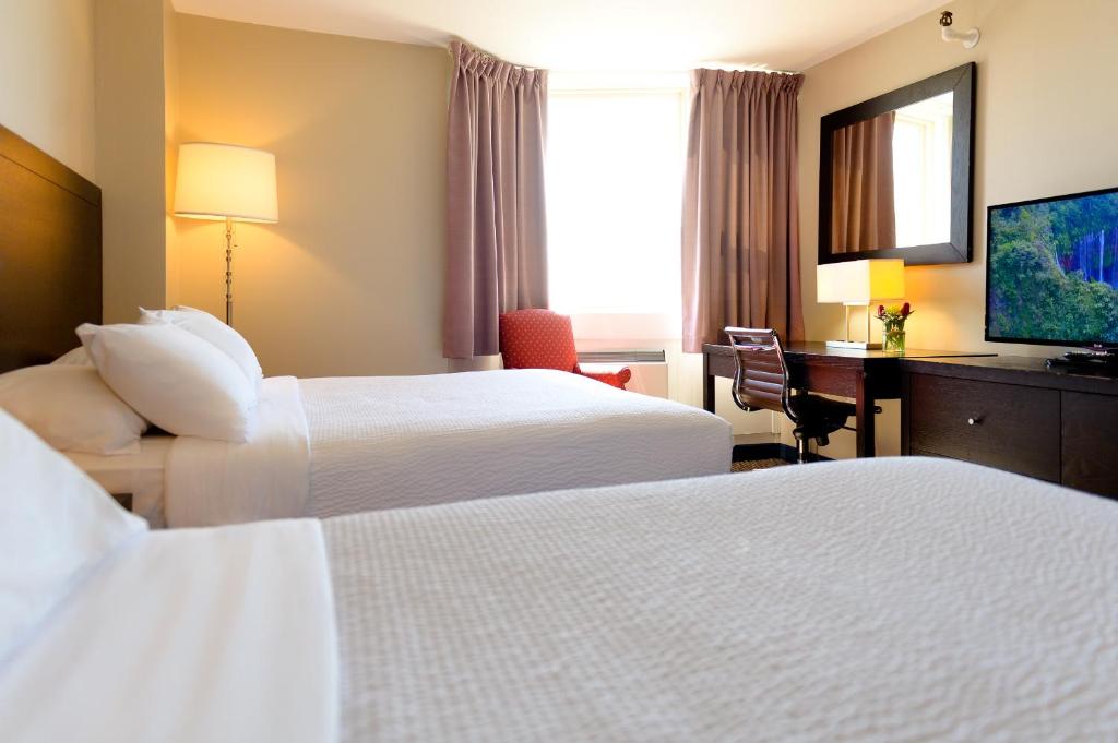 a hotel room with two beds and a desk and a television at Rodd Grand Yarmouth in Yarmouth