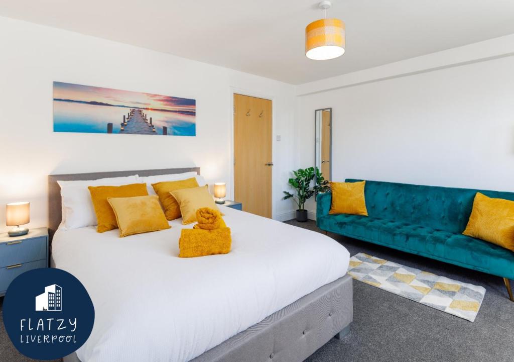 a bedroom with a white bed and a blue couch at FLATZY - Modern Apartment Close to Football Stadiums in Liverpool