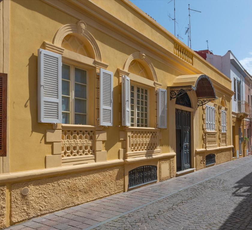 ein gelbes Gebäude mit weißen Rollläden auf einer Straße in der Unterkunft Casa Anna in Carloforte