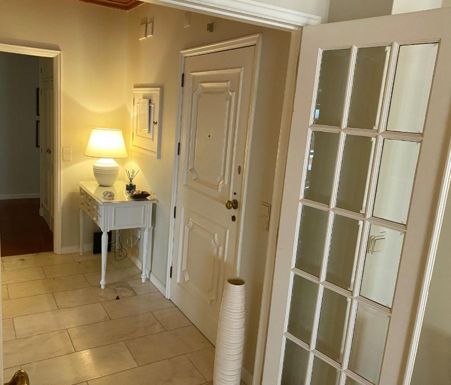 einen Flur mit einer weißen Tür und einem Tisch mit einer Lampe in der Unterkunft Apartamento Ruy Belo - Foz in Vila do Conde